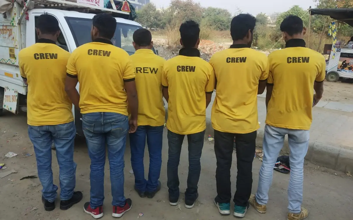 A six-person moving crew in CREW T-shirts beside a loading vehicle